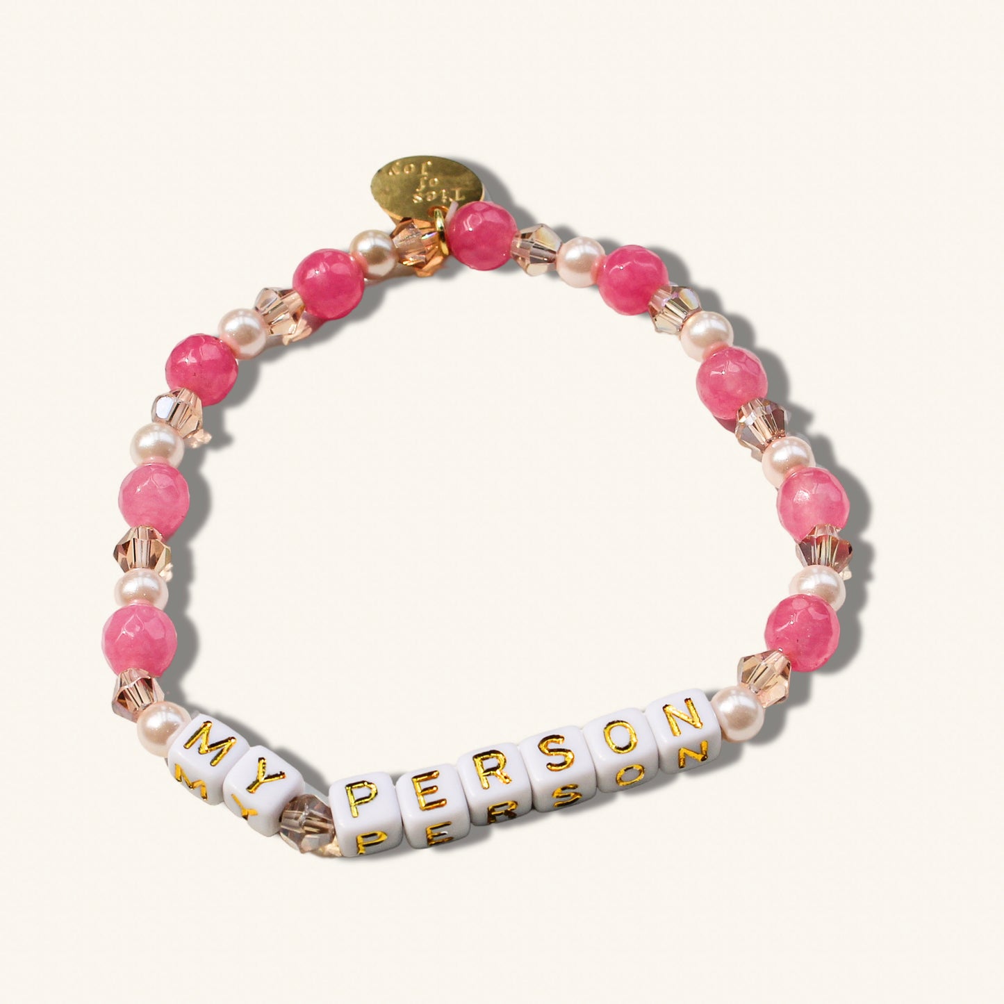 Bracelet with pink beads, pearls, and gold accents on a white background
