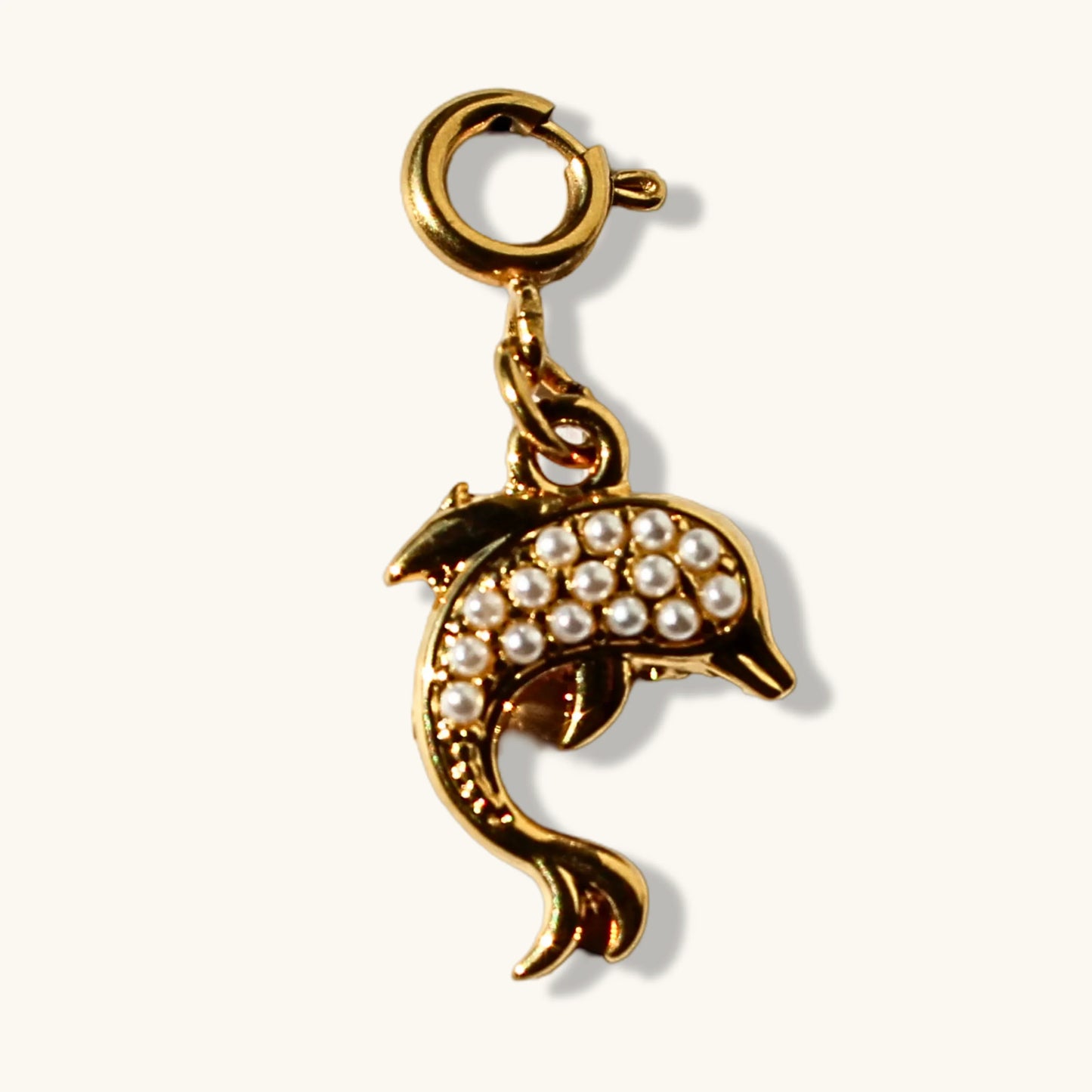 Gold dolphin charm with pearl accents and lobster clasp on white background