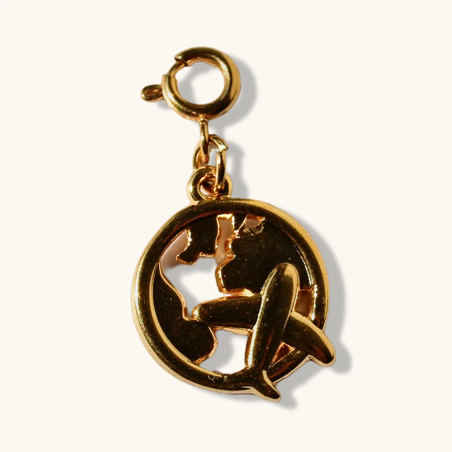 Gold airplane and globe travel charm pendant on a white background