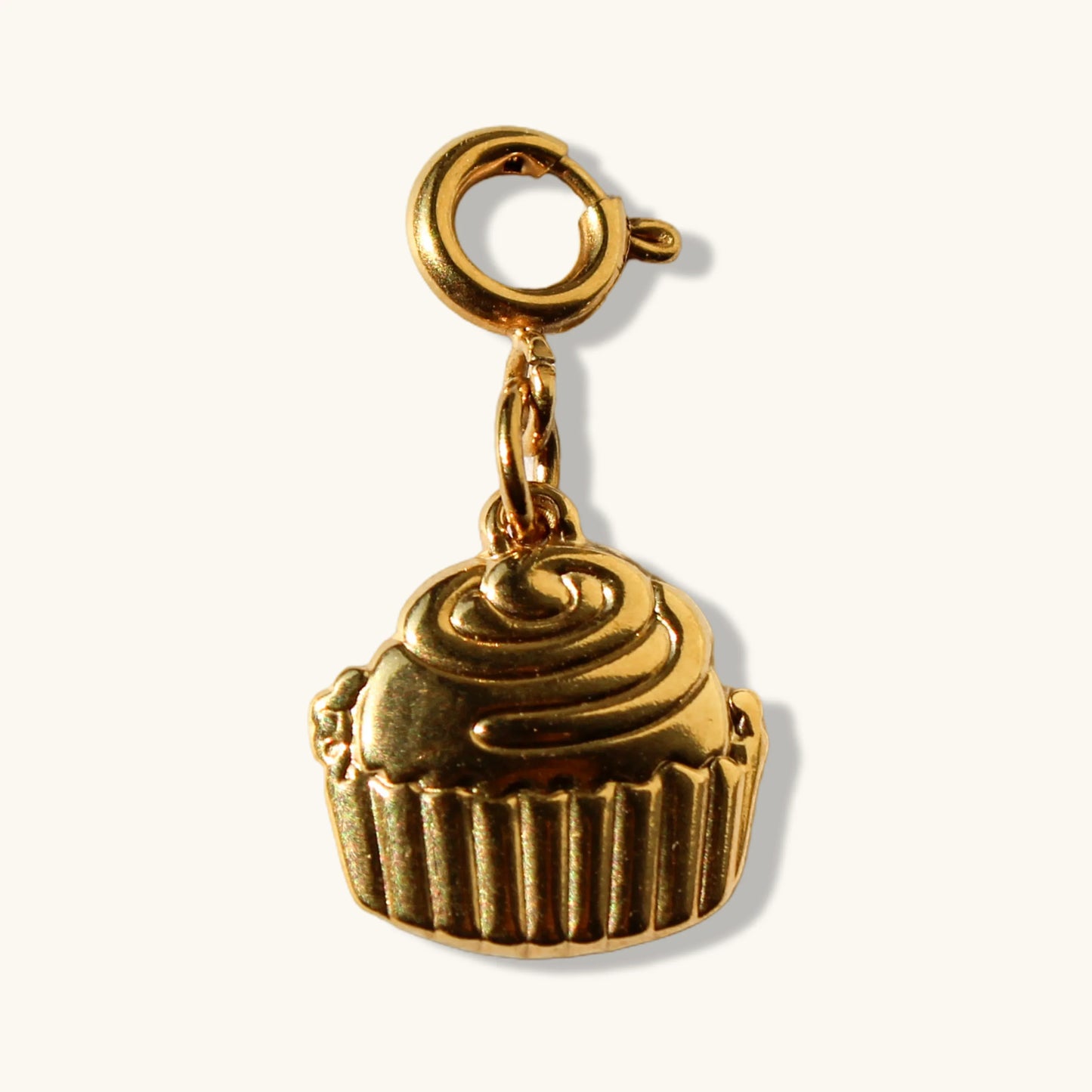 Gold cupcake charm pendant with clasp on a plain light background