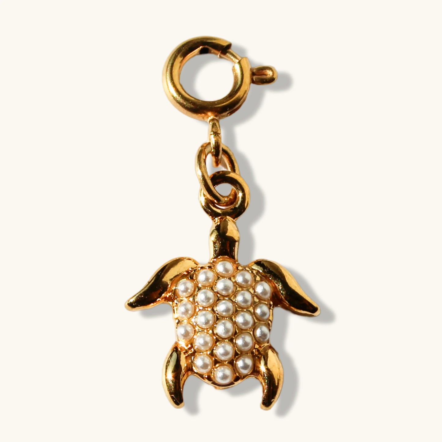 Gold turtle pendant charm with pearl accents on cream background