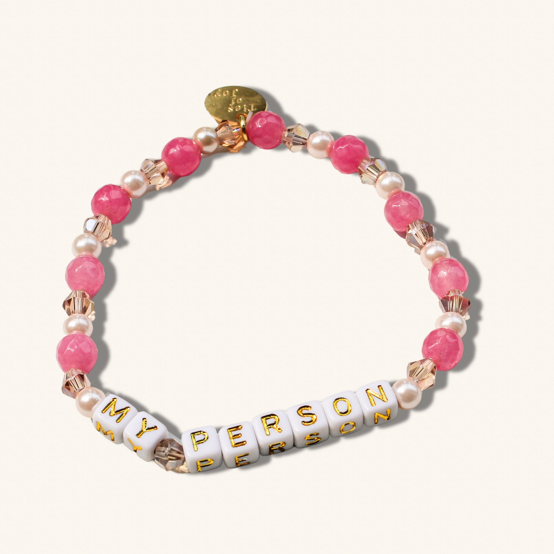 Bracelet with pink beads, pearls, and gold accents on a white background