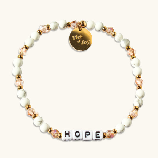 Hope beaded bracelet with white and gold beads, pink crystals, and Ties of Joy charm