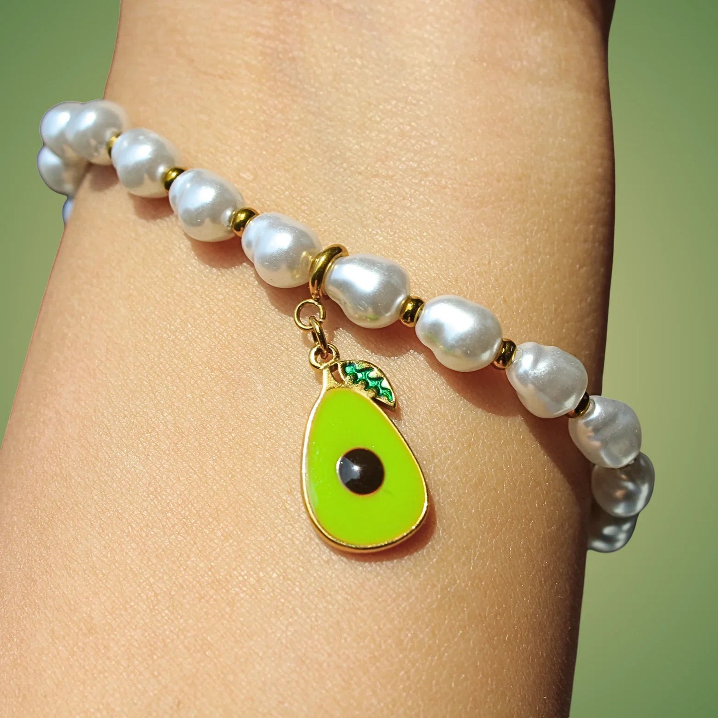 Pearl beaded bracelet with avocado charm on wrist, jewelry close-up