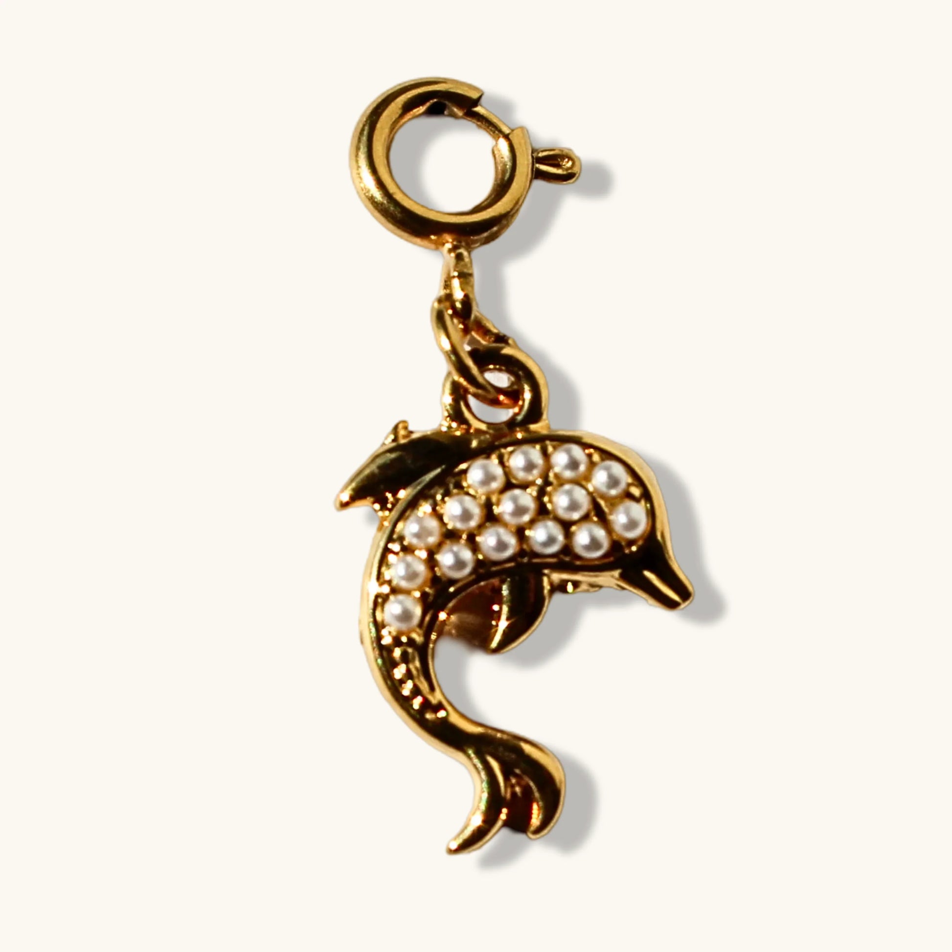 Gold dolphin charm with pearl accents and lobster clasp on white background
