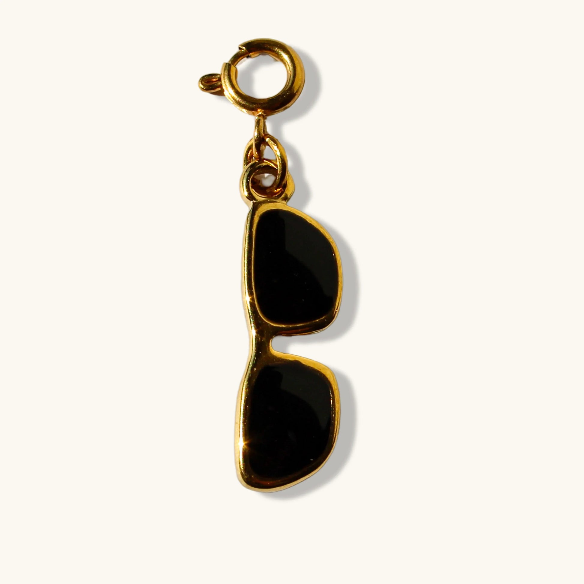 Gold sunglasses charm with black enamel pendant on a white background