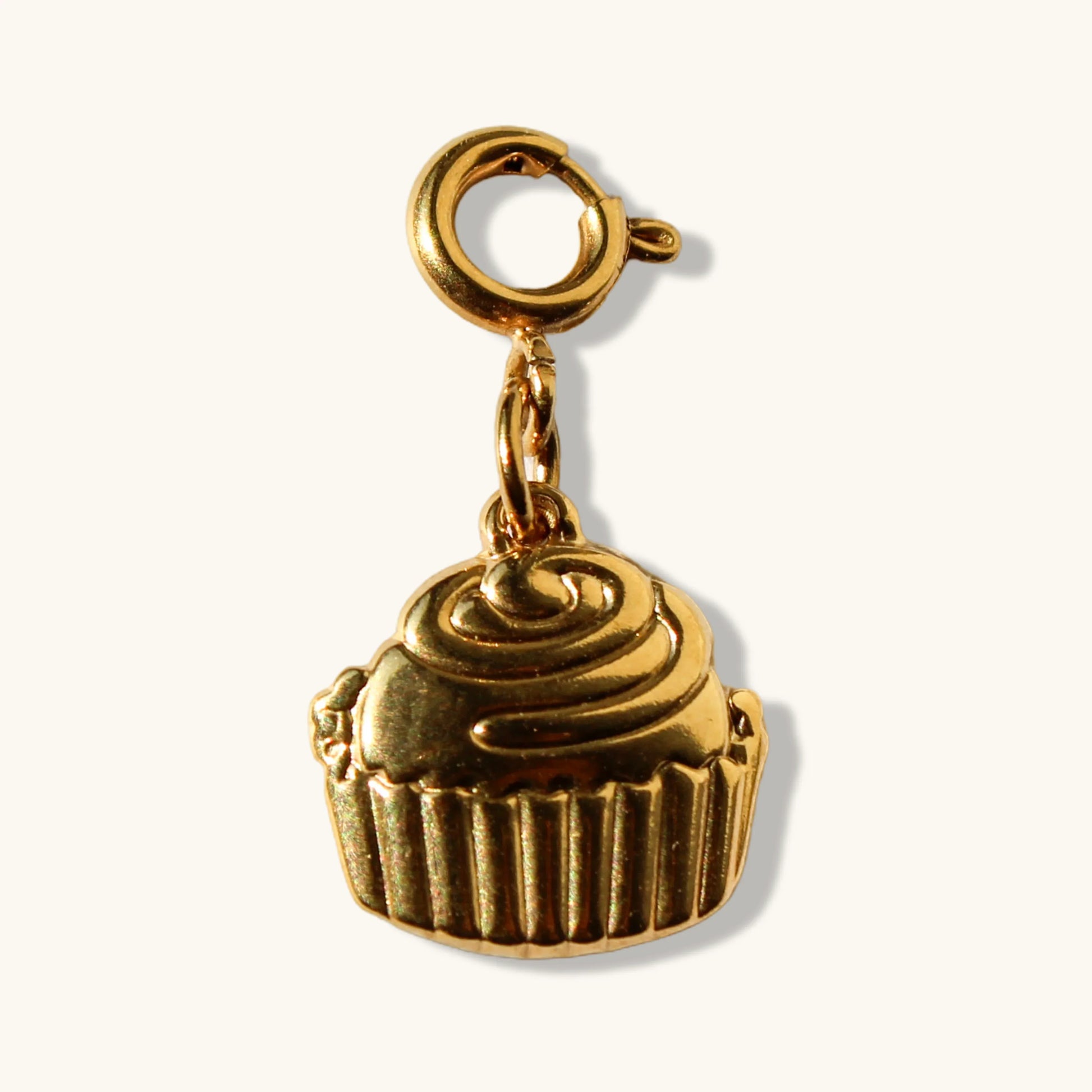 Gold cupcake charm pendant with clasp on a plain light background