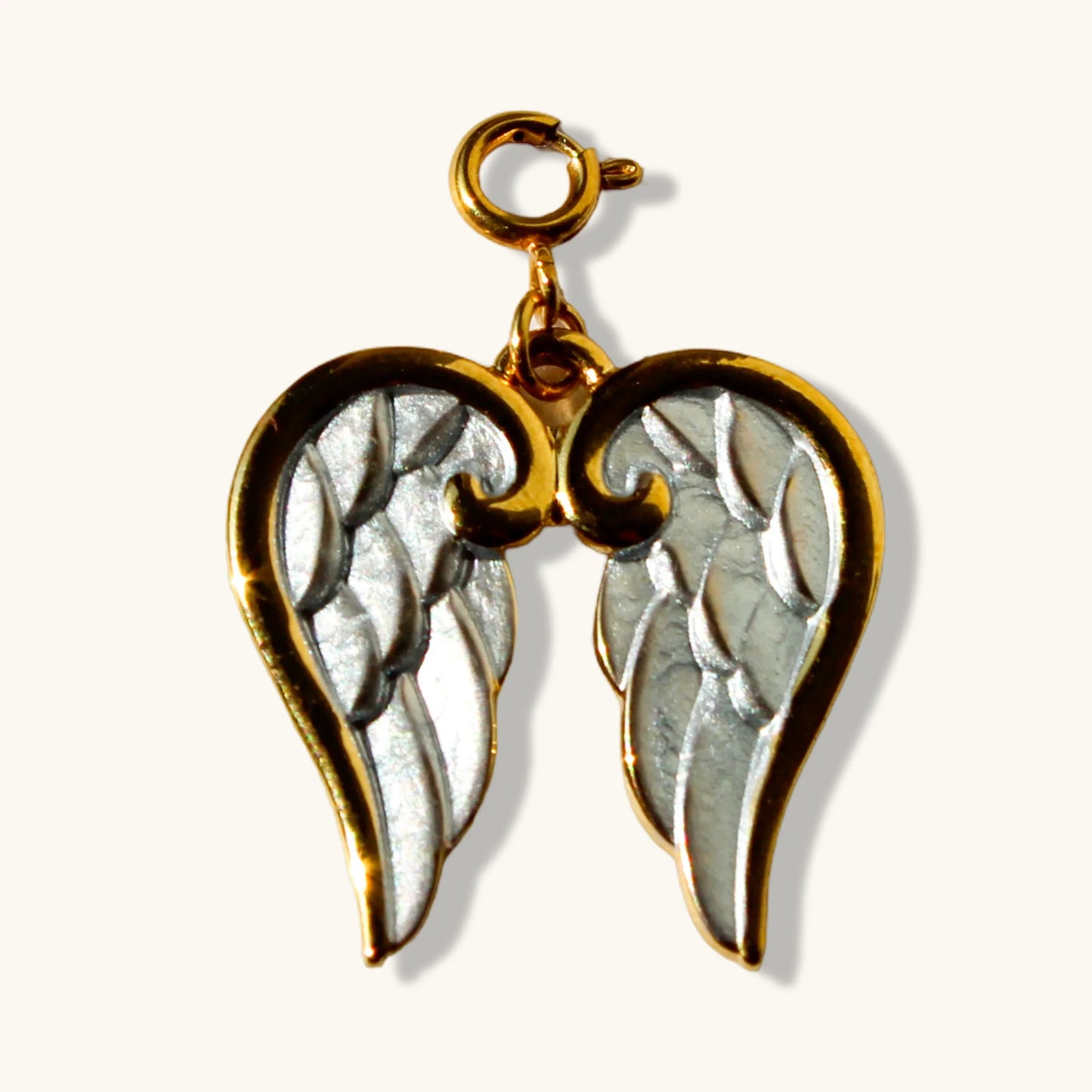 Gold and silver angel wing pendant charm against a light background