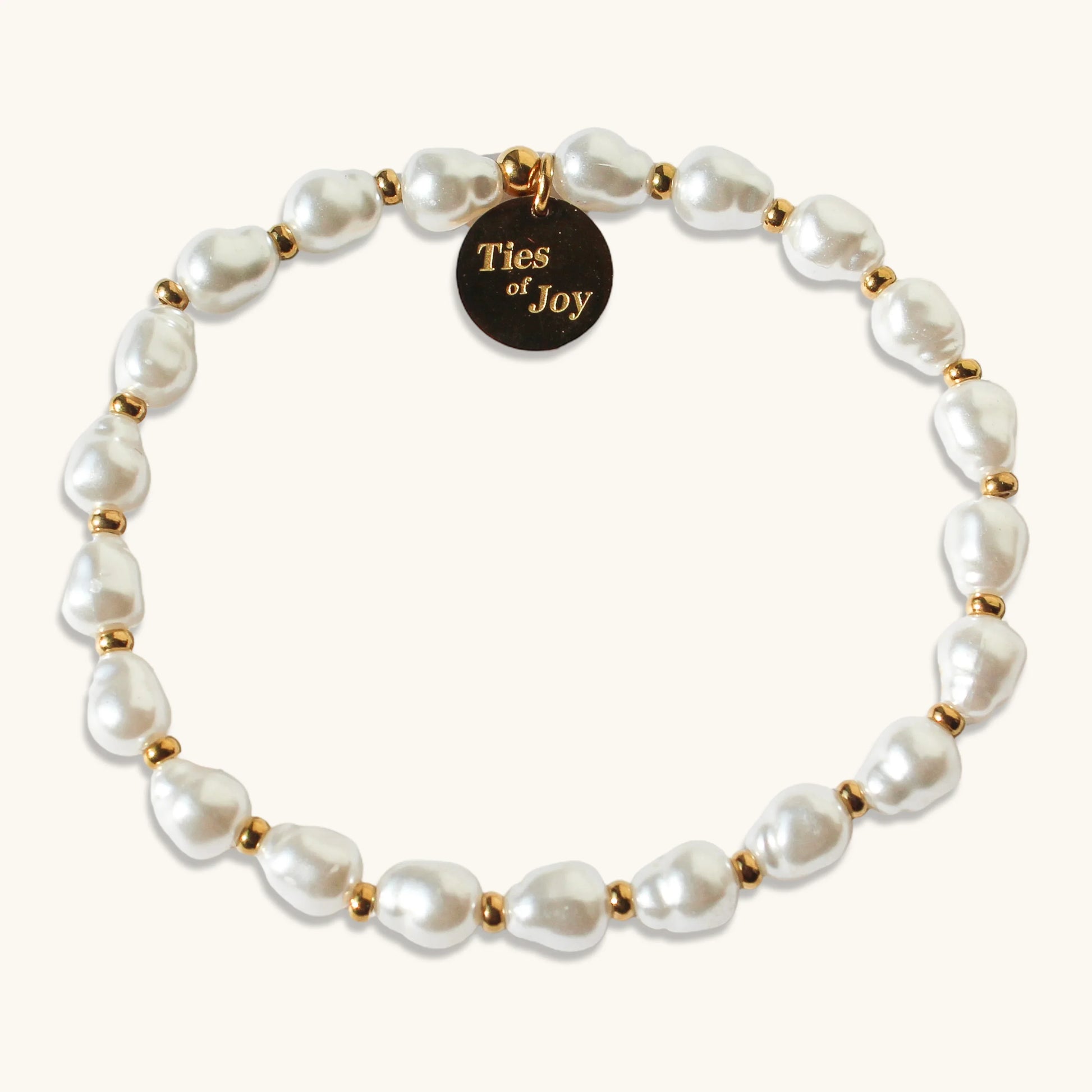 Pearl beaded bracelet with gold accents and Ties of Joy round charm on a light background
