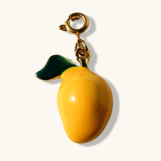 Yellow mango charm pendant with gold clasp and green leaf on cream background