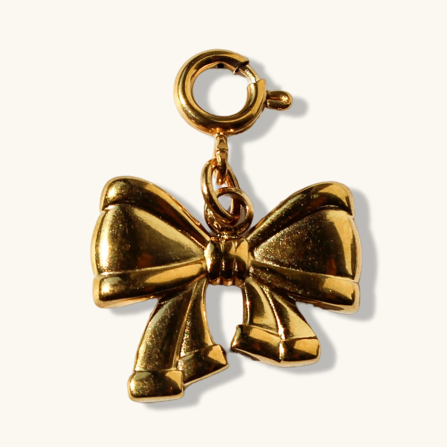 Shiny gold bow charm with clasp on plain light background