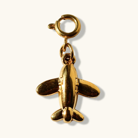 Gold airplane charm pendant with clasp on a plain light background
