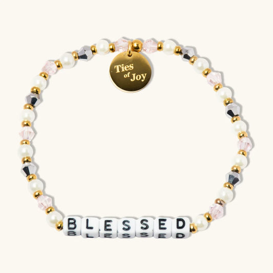 Blessed beaded bracelet with pearls, gold accents, and Ties of Joy charm on cream background